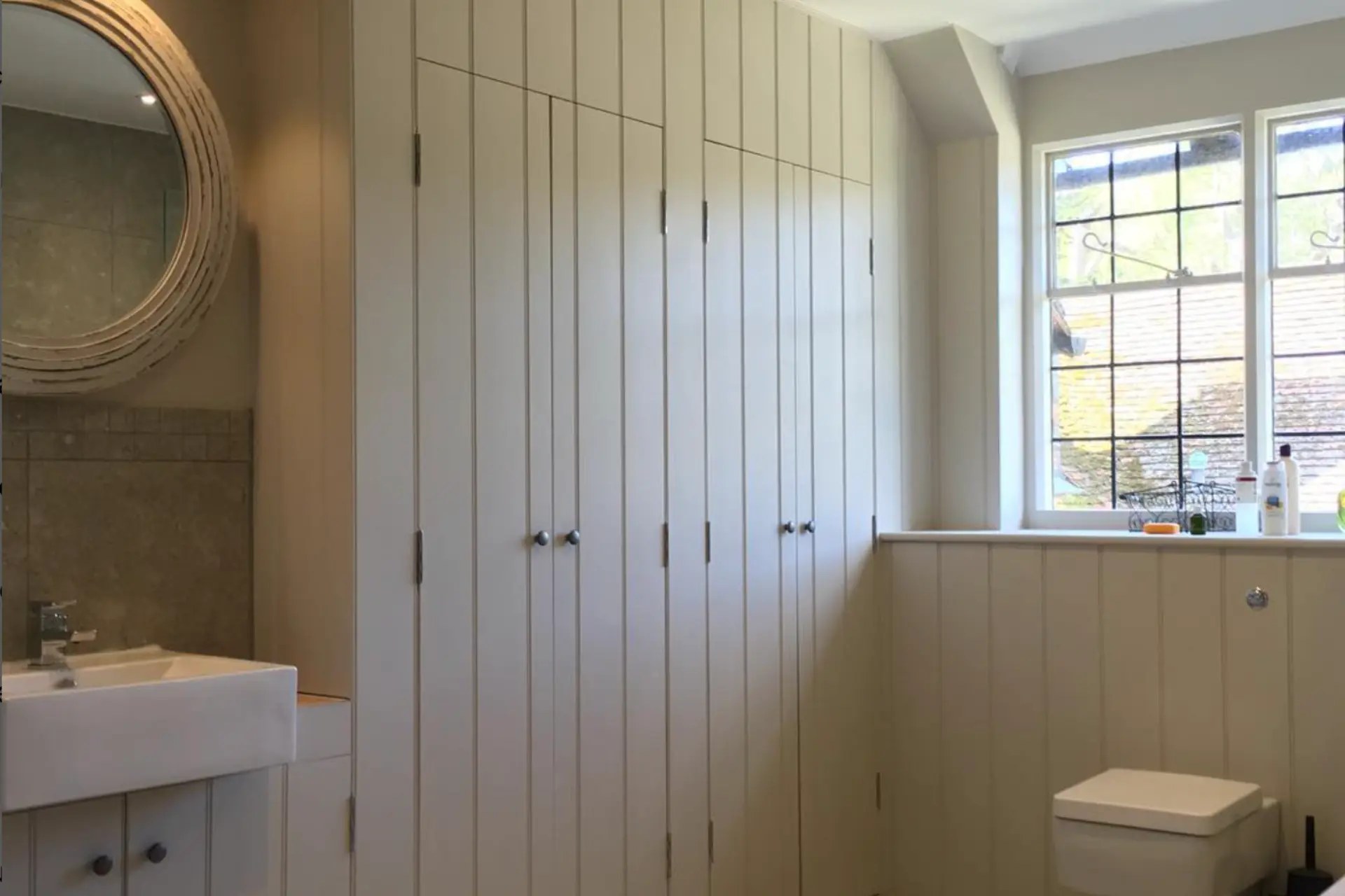 Fitted panelled storage and wall panelling in a bathroom